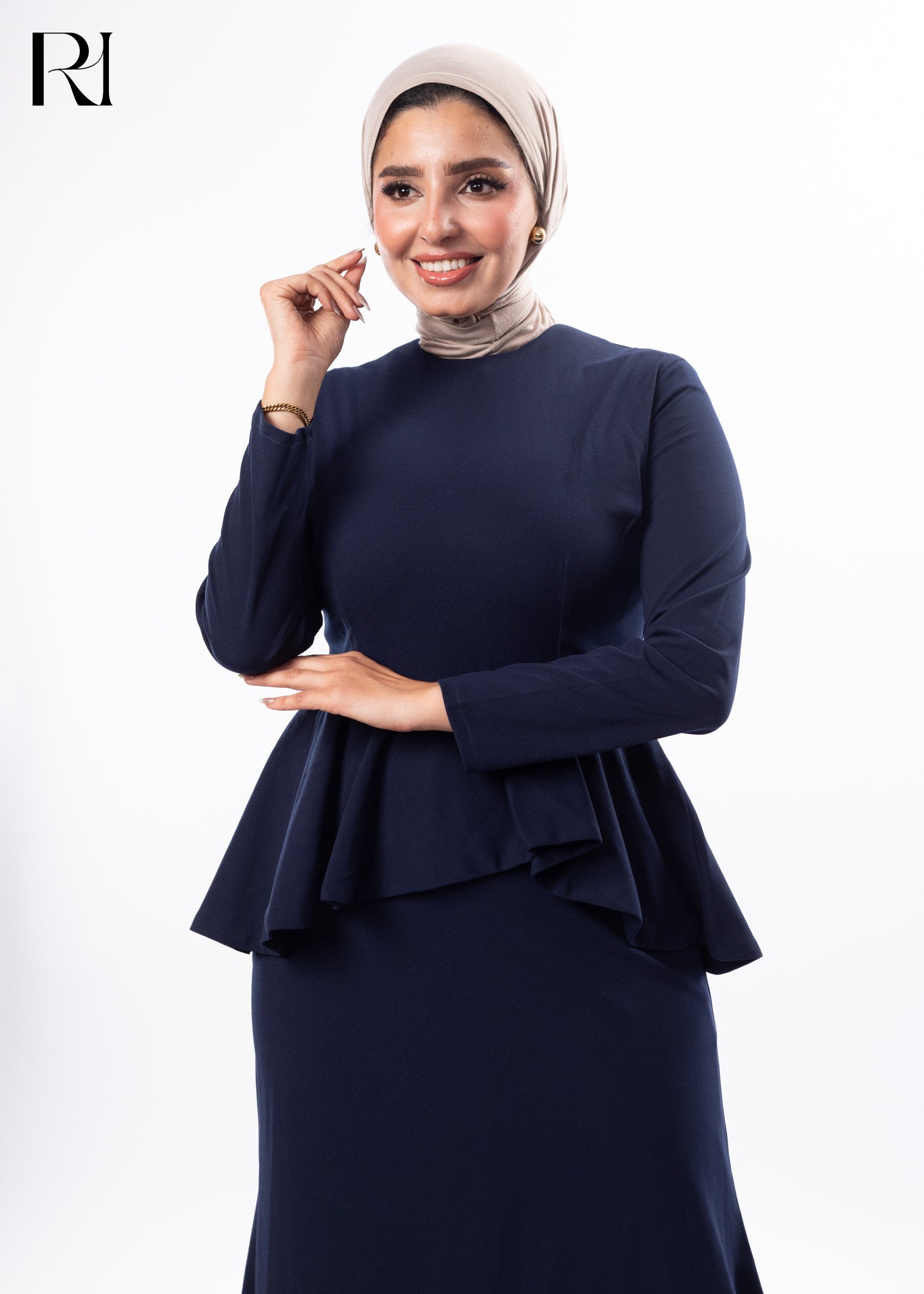 Woman wearing a navy blue peplum dress with a hijab on a white background