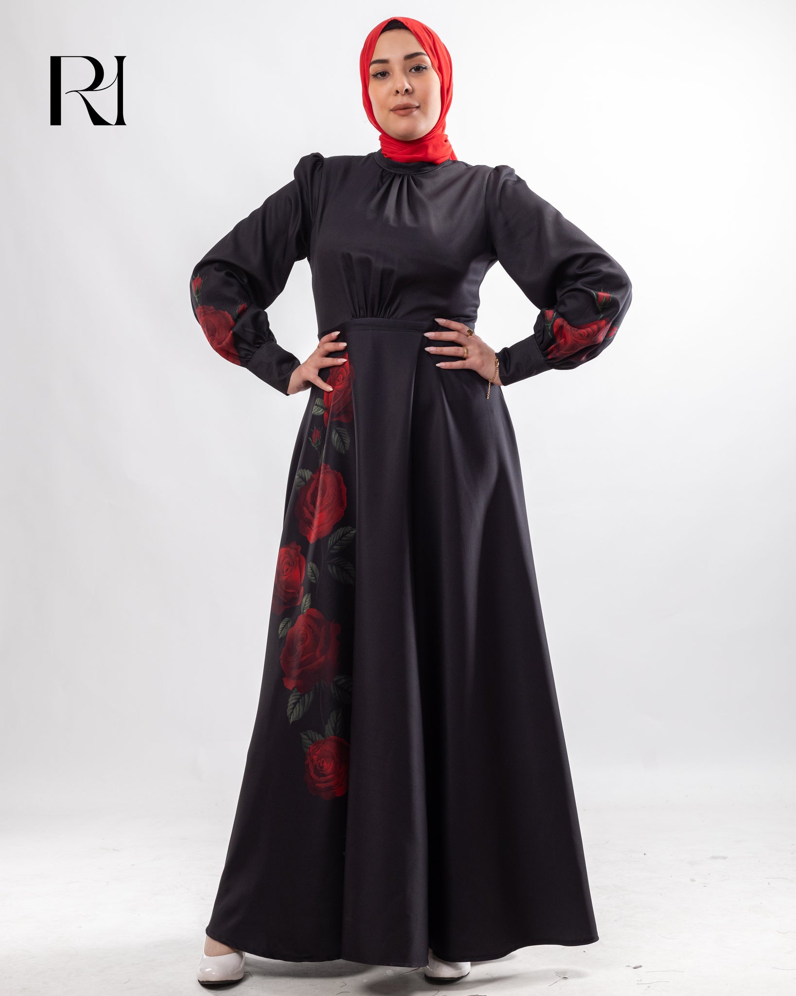 Woman wearing a black dress with red floral patterns and a matching headscarf on a white background.