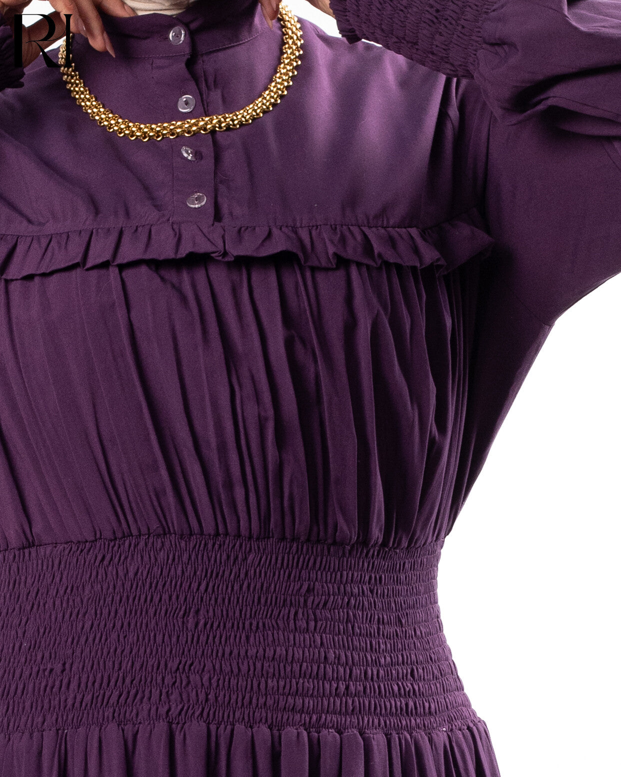 Close-up of a purple dress with ruffled details and a gold necklace.