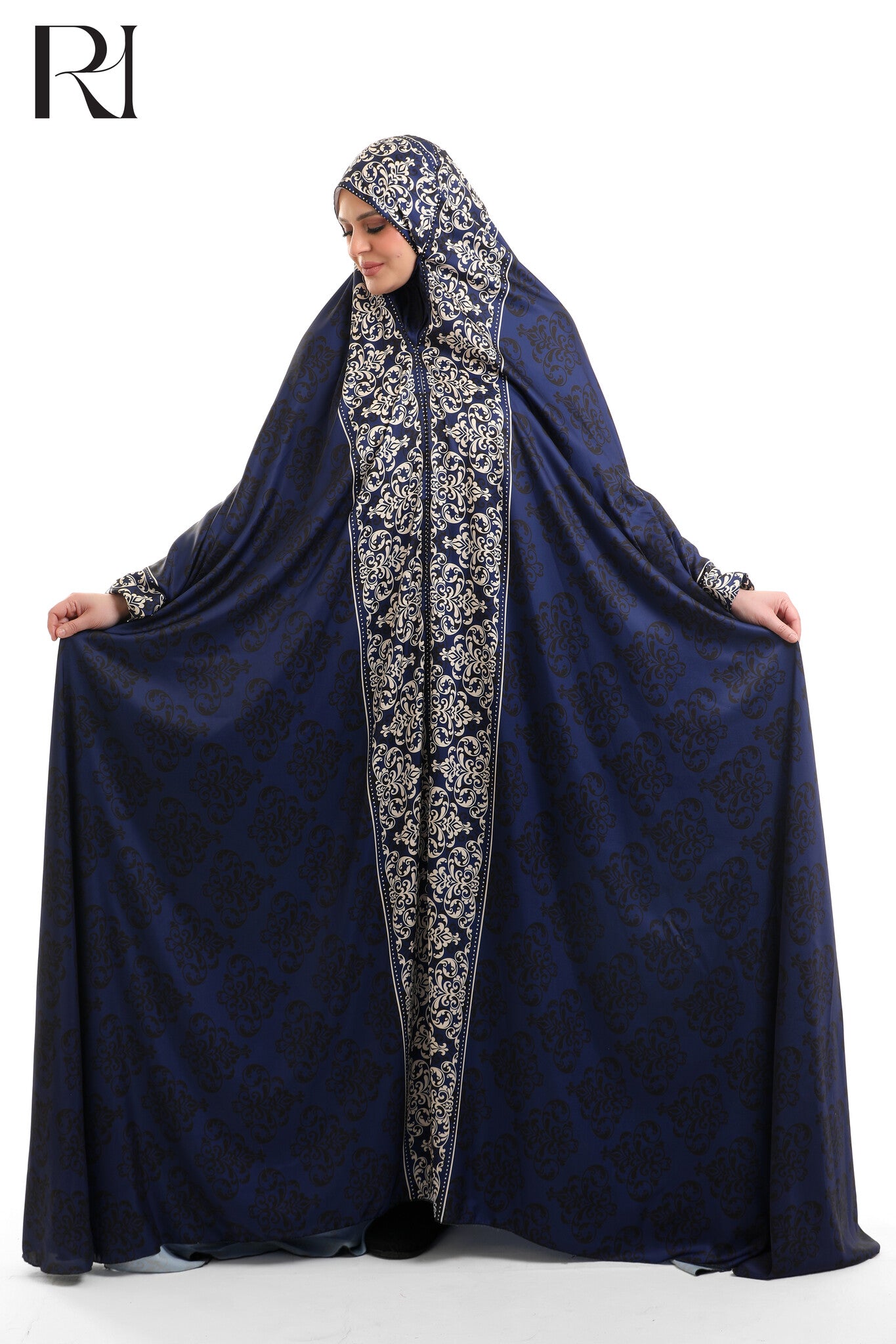 Woman wearing a dark blue abaya with intricate white patterns on a white background