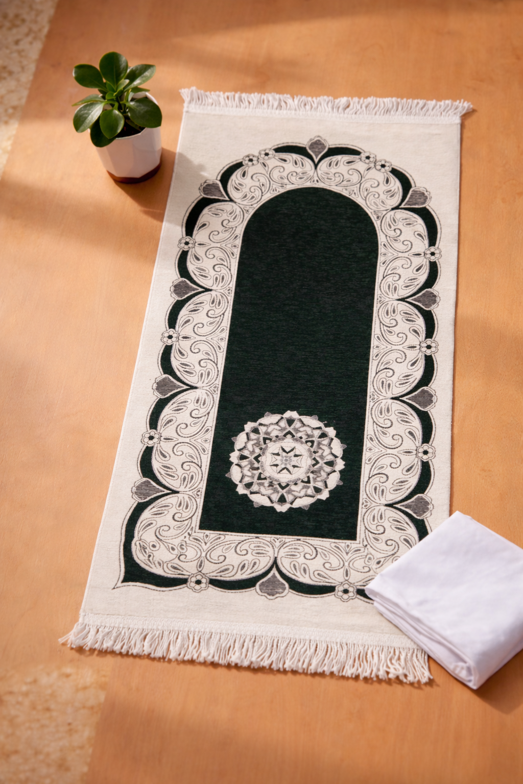 Decorative prayer mat with intricate black and white design on a wooden surface.