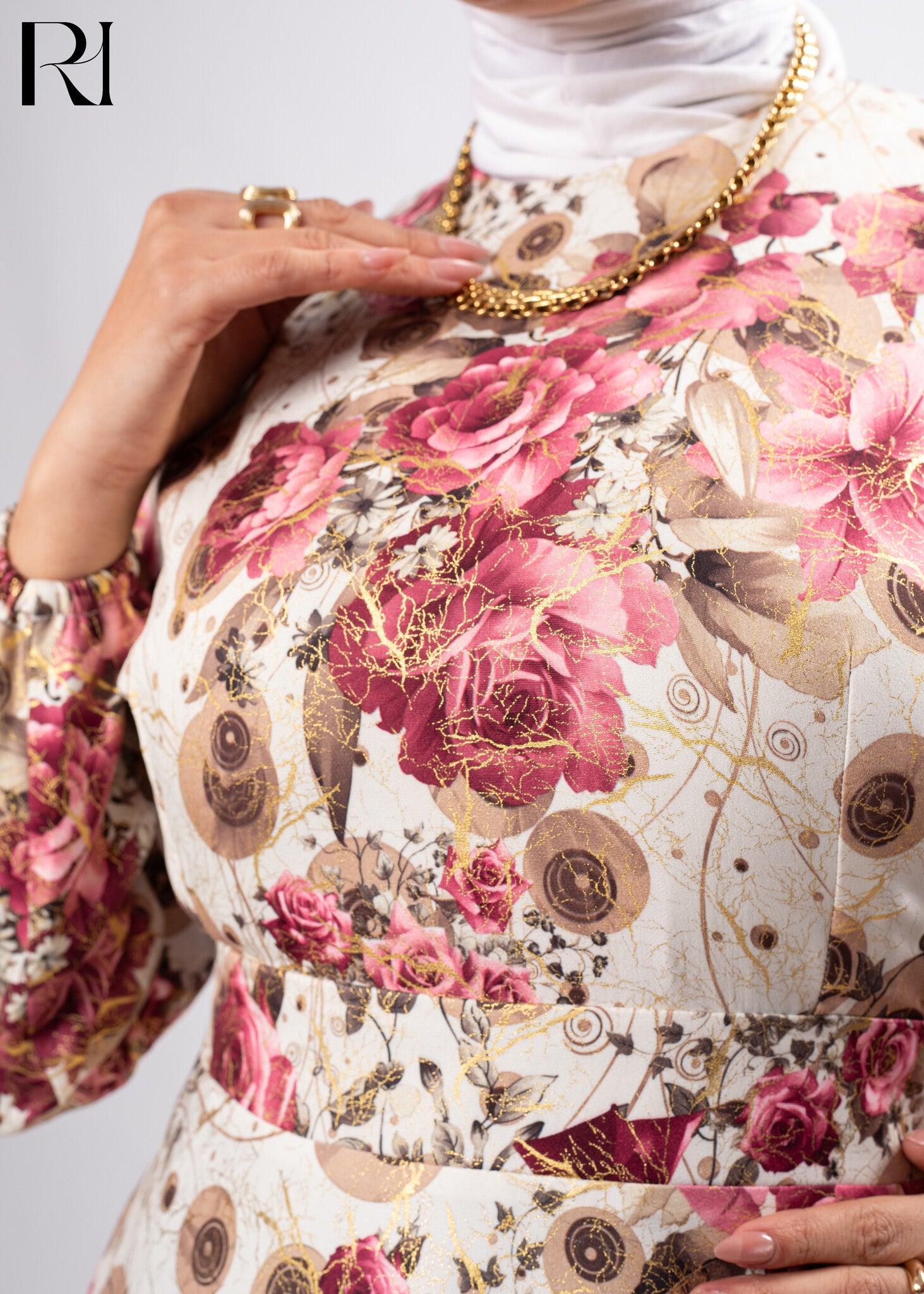 Floral patterned garment with gold accents and a brand logo in the corner.