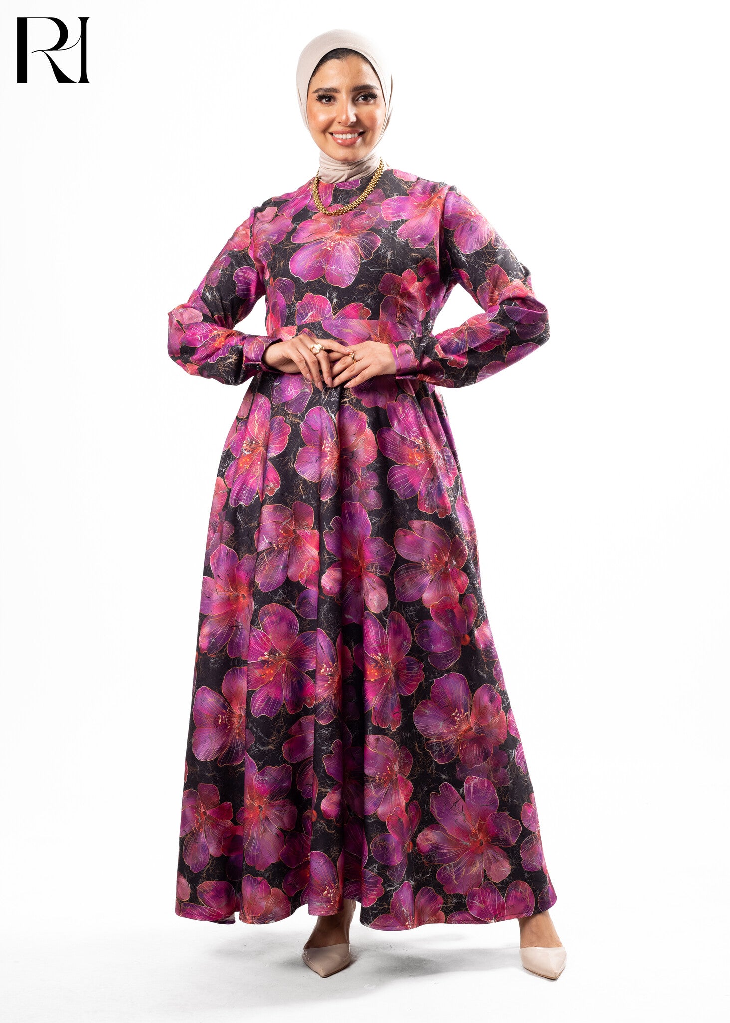 Woman wearing a long, floral-patterned dress with a white hijab on a white background
