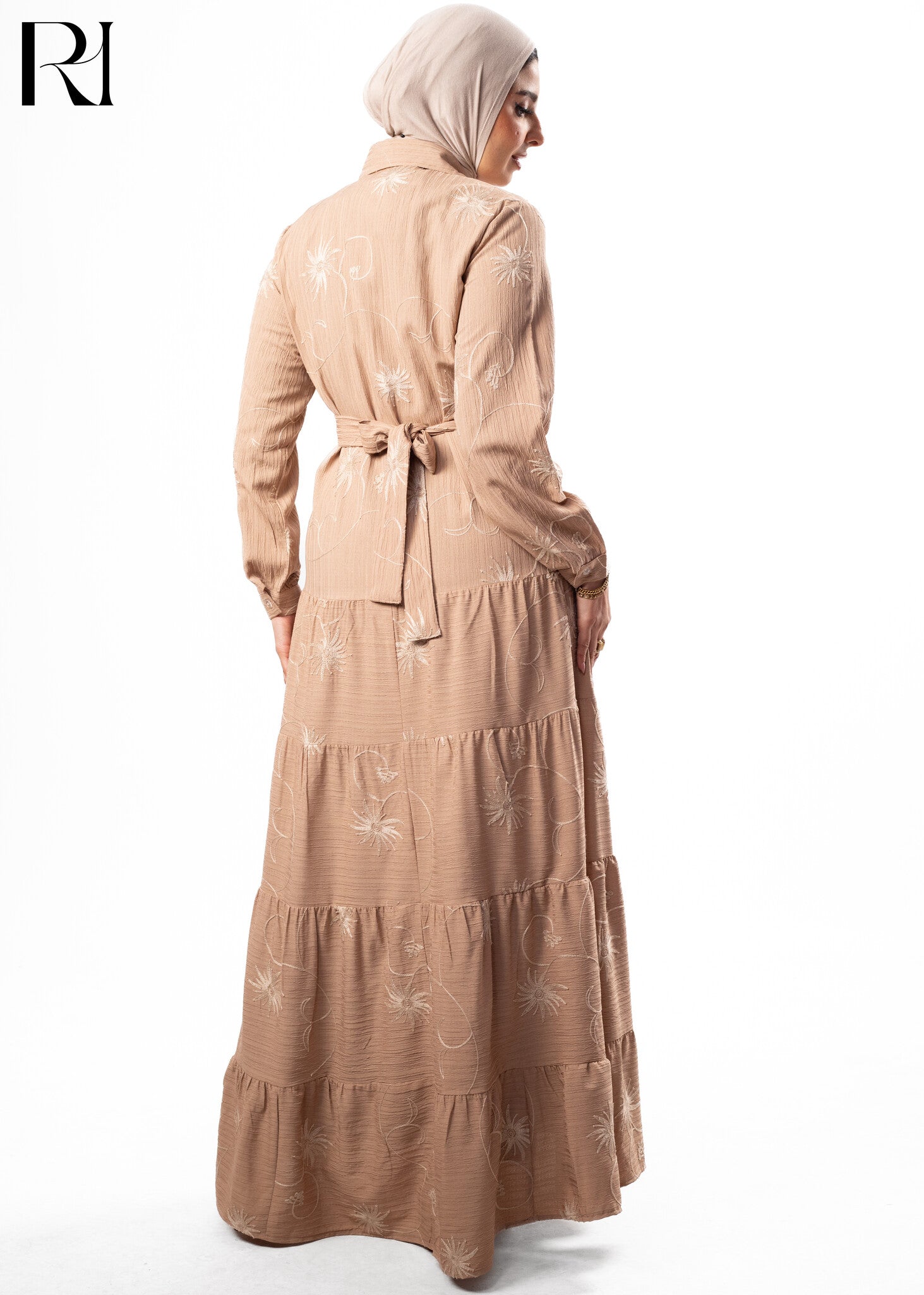 Woman wearing a beige dress with floral patterns on a white background