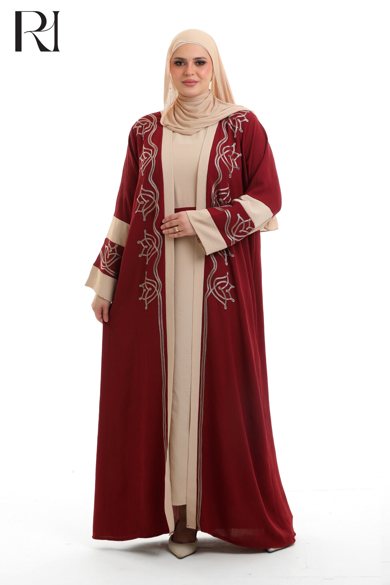 Woman wearing a burgundy and beige abaya with intricate patterns on a white background