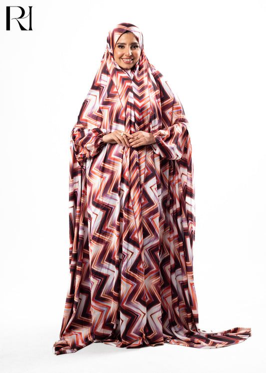 Woman wearing a patterned abaya on a white background with 'RI' logo.