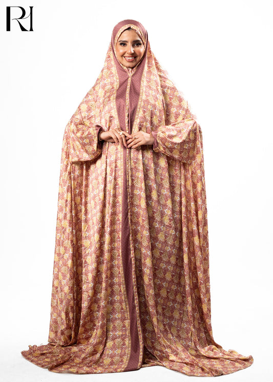 Woman wearing a long, patterned dress with a hijab on a white background