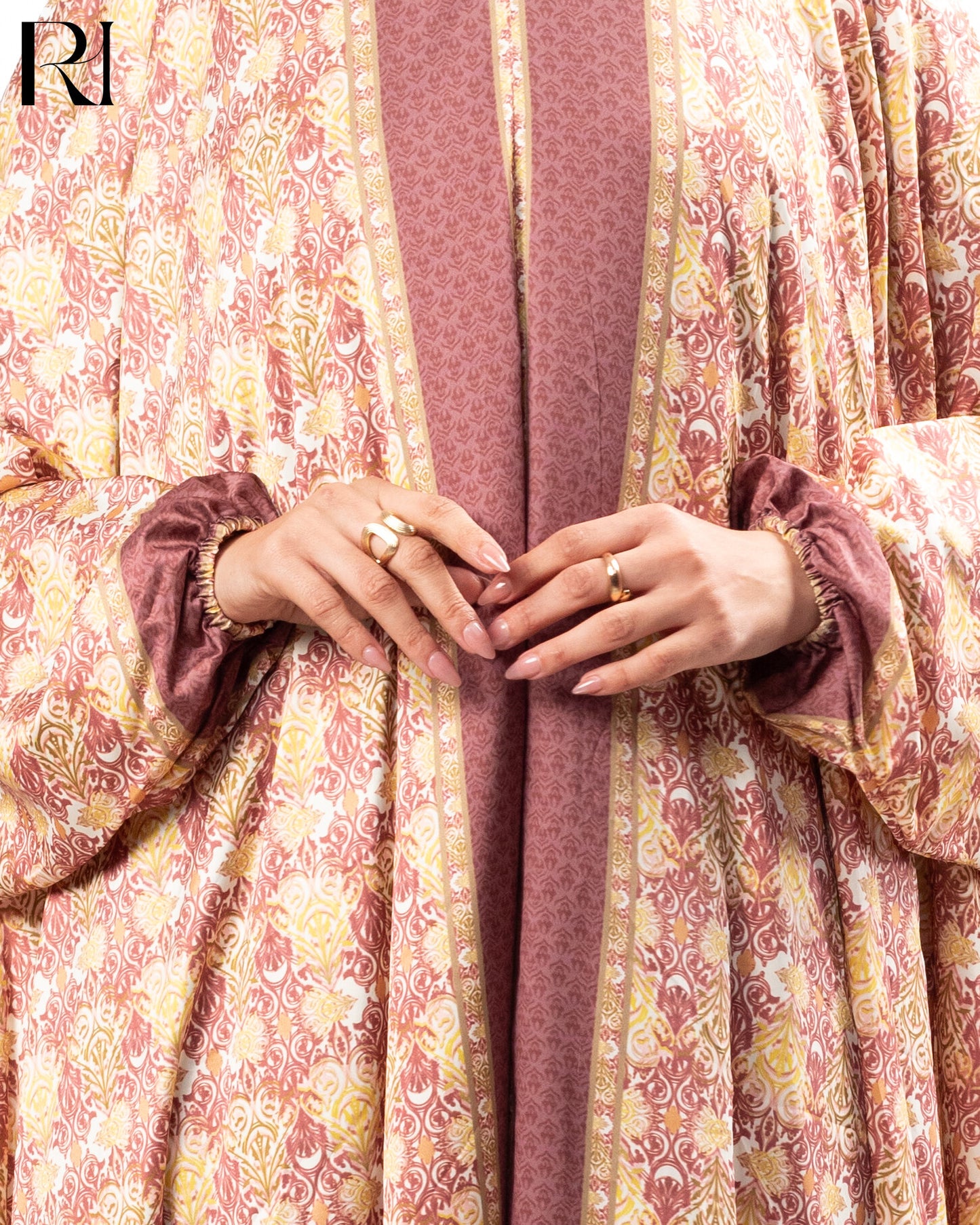 Close-up of hands making a heart shape with a patterned garment in the background