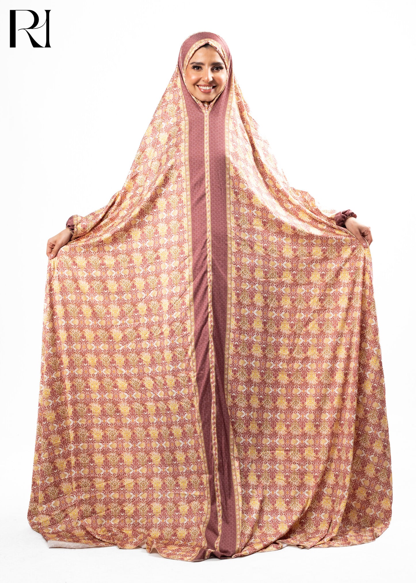 Woman wearing a patterned abaya with a hood on a white background, featuring the brand 'RI'.
