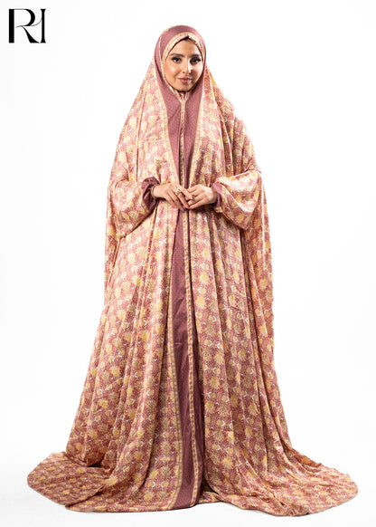 Woman wearing a patterned abaya with a hijab on a white background, featuring the brand 'RI'.