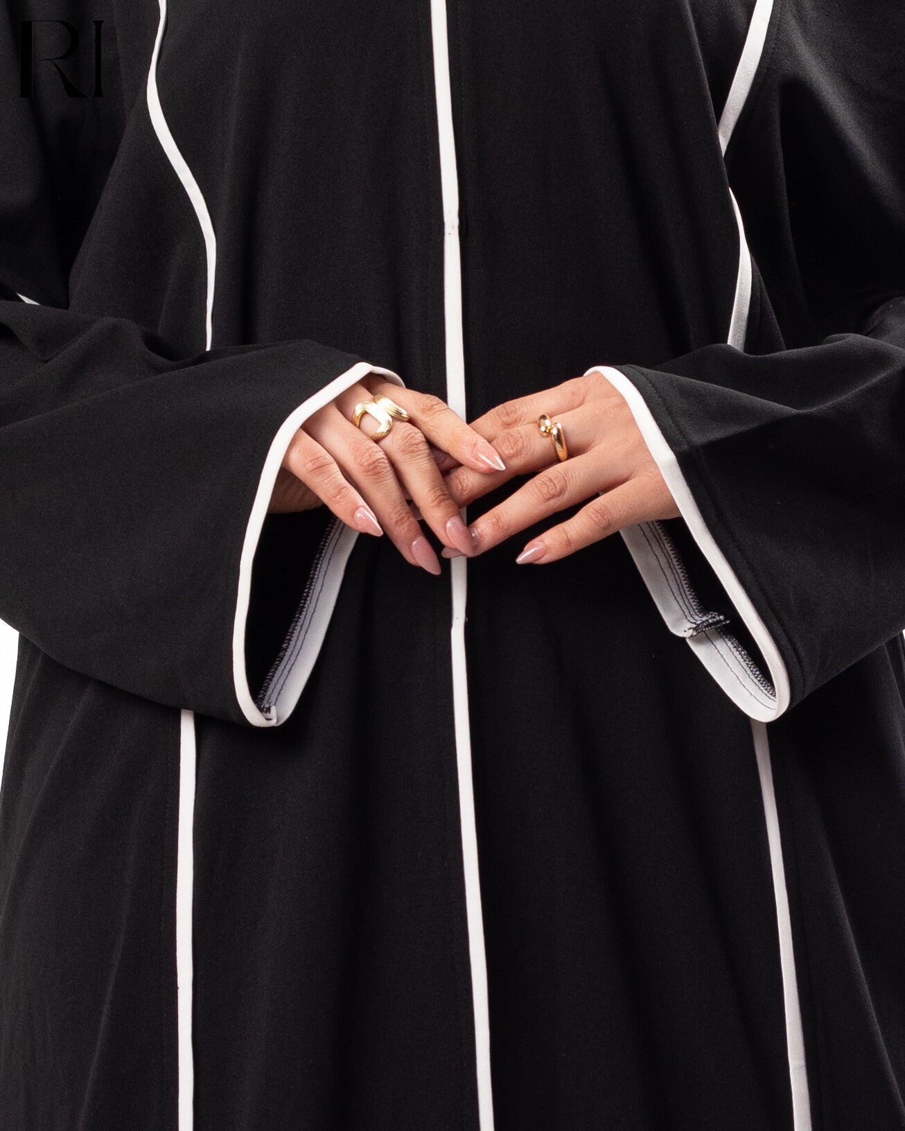 Close-up of hands wearing rings on a black garment with white trim