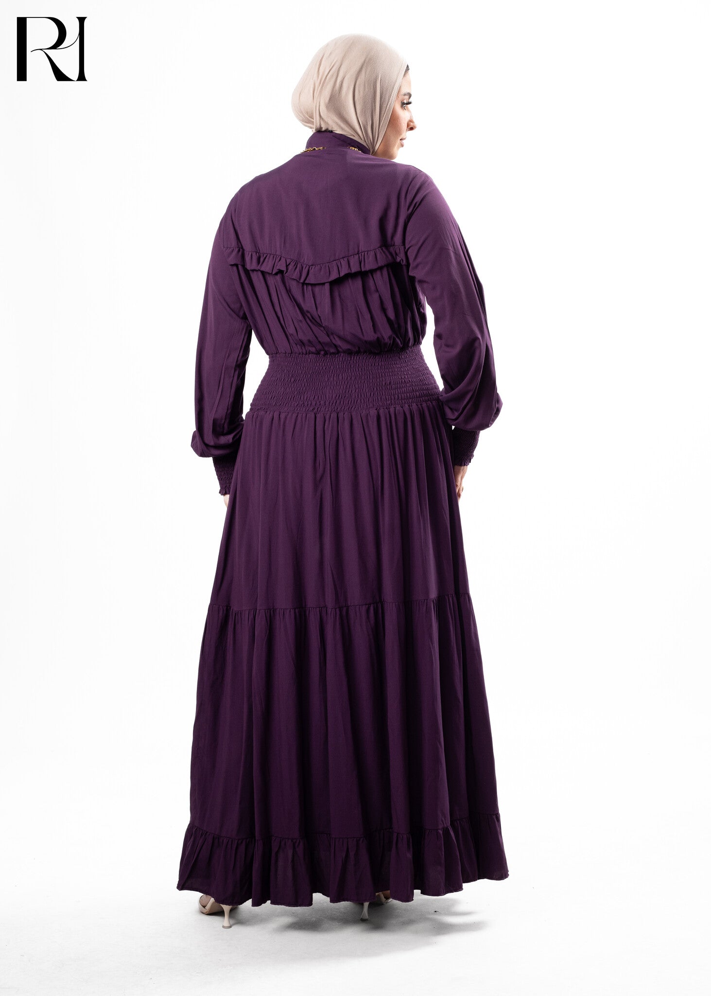 Woman wearing a long purple dress with ruffled details on a white background
