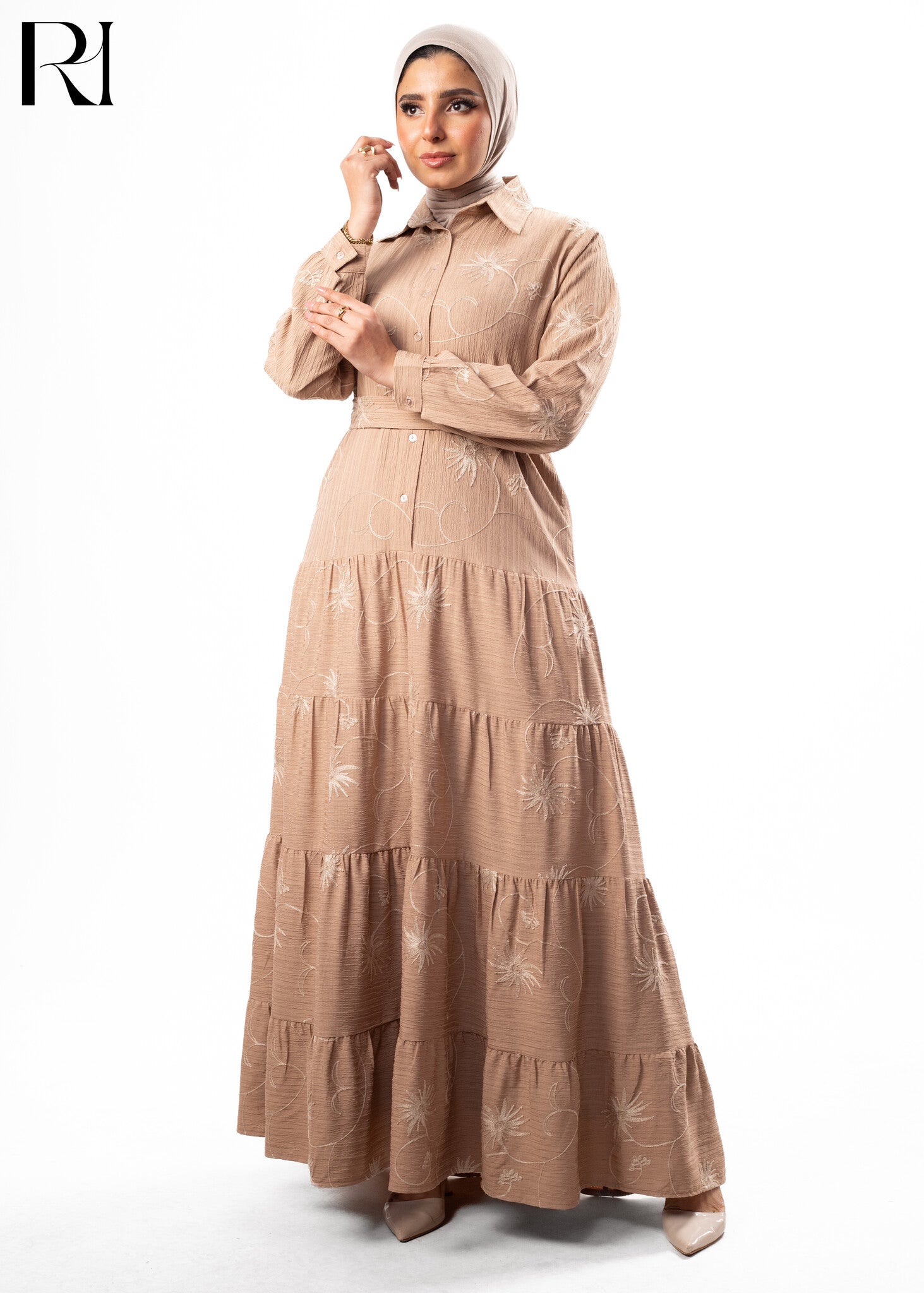 Woman wearing a beige long dress with floral patterns on a white background