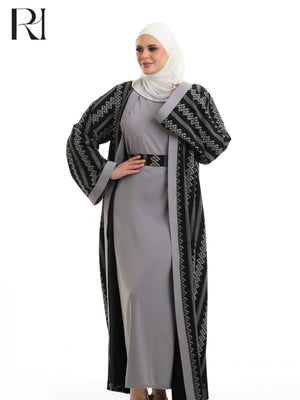 Woman wearing a long black and white patterned coat over a gray dress on a white background