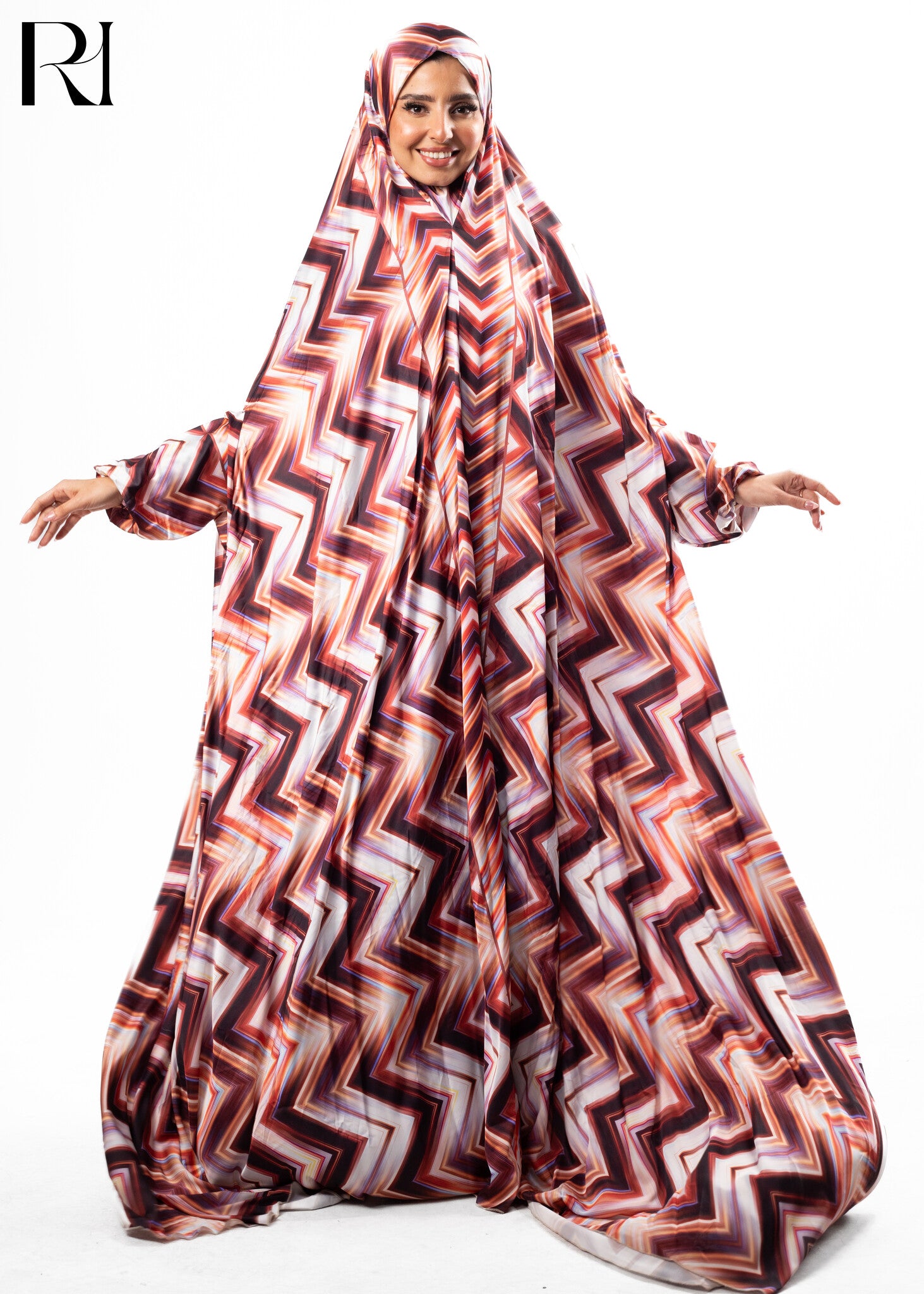 Woman wearing a patterned abaya with a visible brand logo on a white background